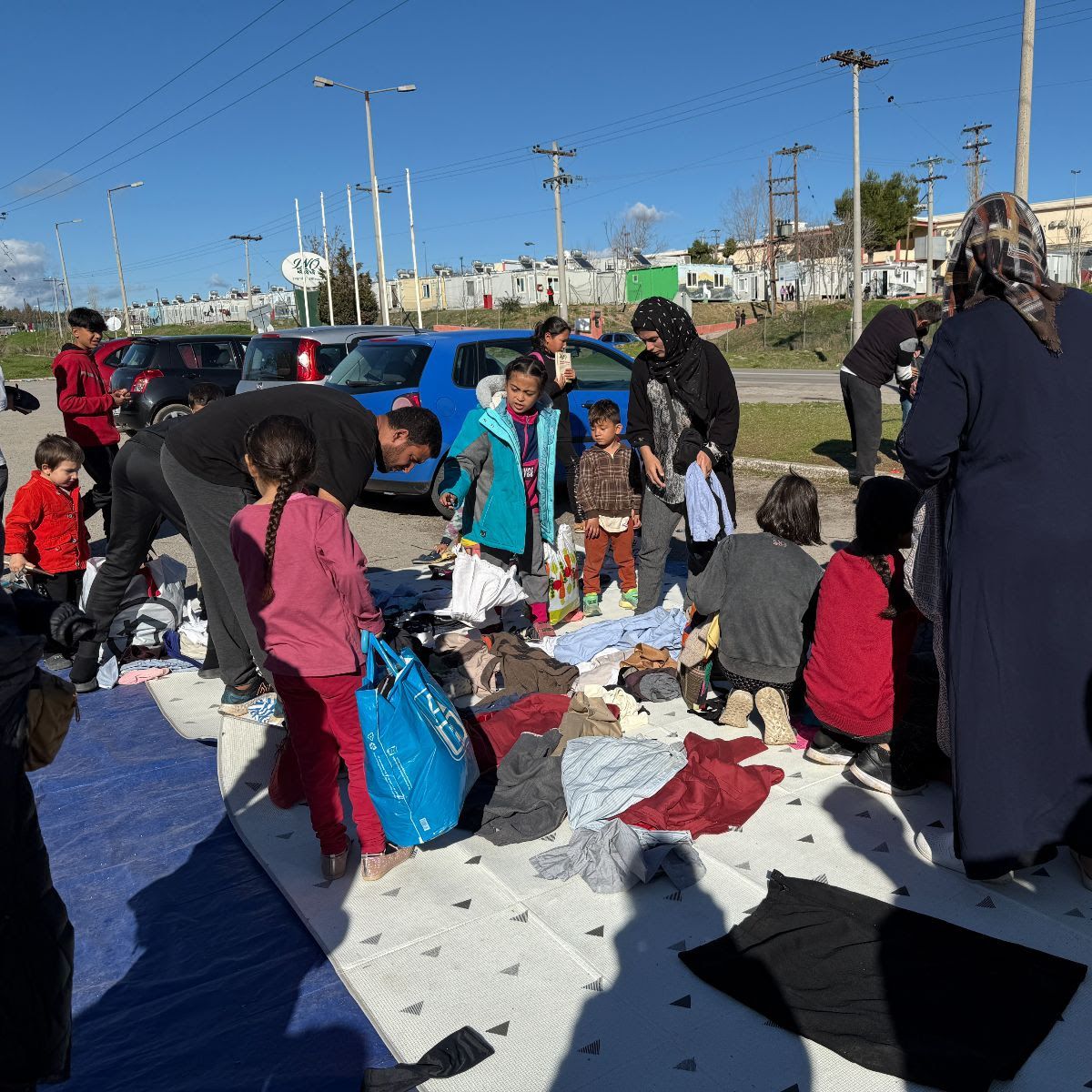 A group of people are gathered on a blanket on the ground