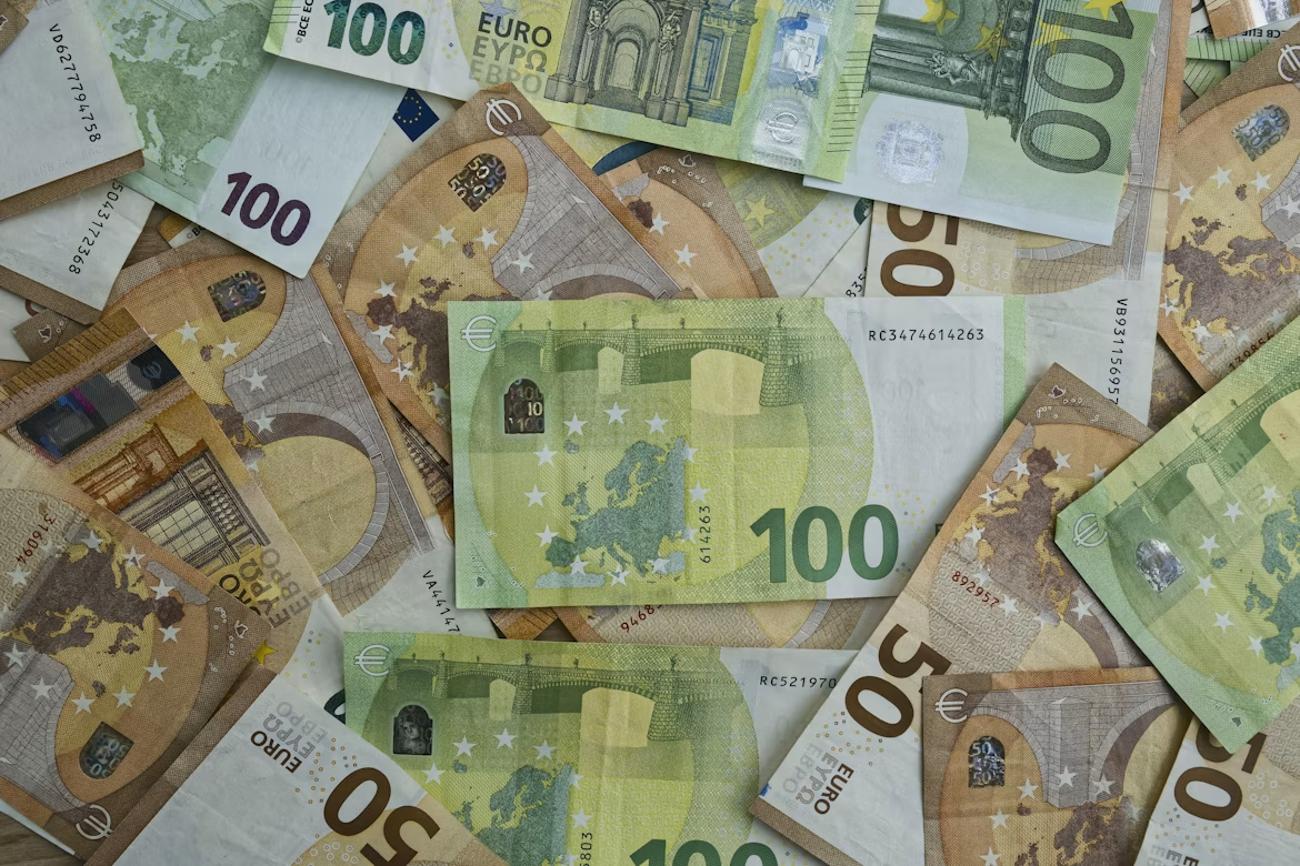 Verspreid liggen eurobankbiljetten, voornamelijk biljetten van 100 en 50 euro in groene en beige kleuren.