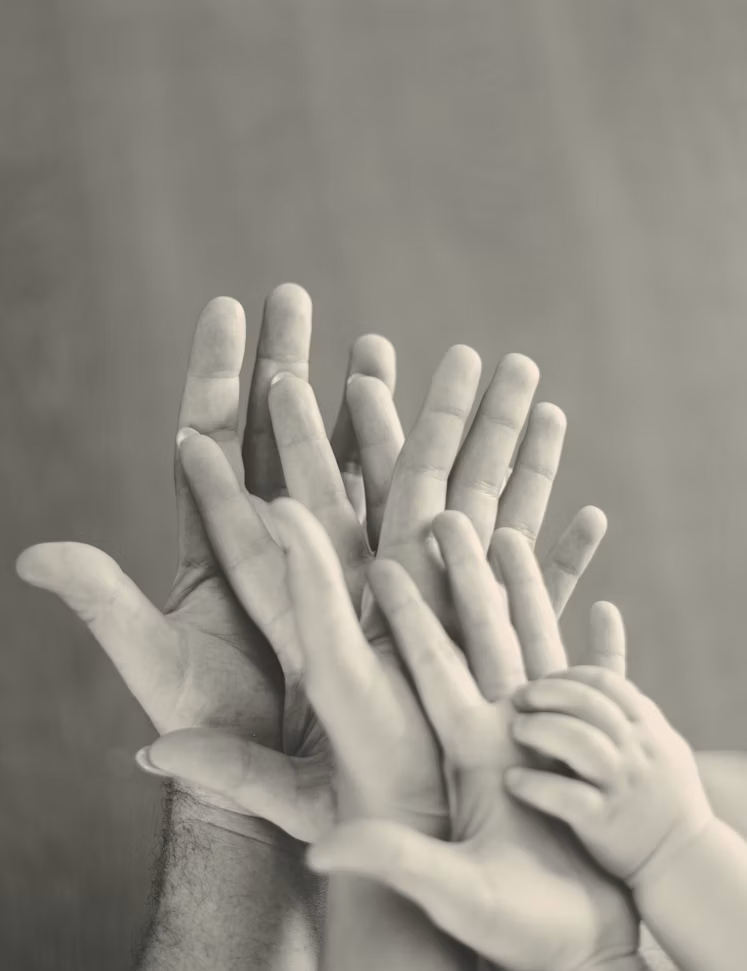 Meerdere handen in zwart-wit van volwassenen en kinderen die een gezin symboliseren. Een symbool voor familiemediation.