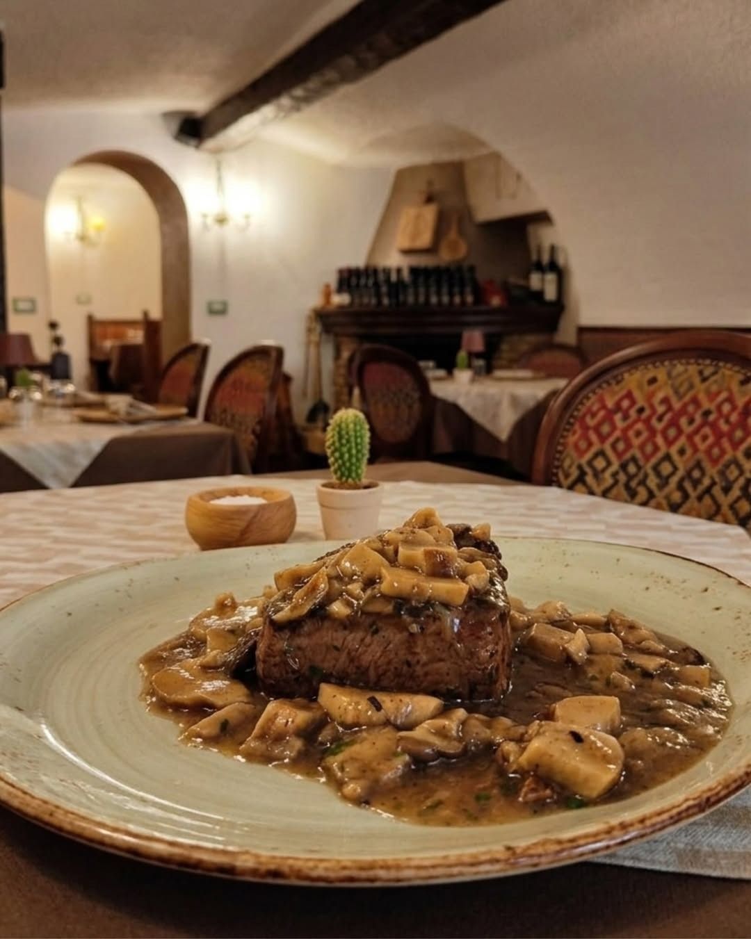 Un piatto di bistecca con salsa ai funghi in un'accogliente sala da pranzo di un ristorante.