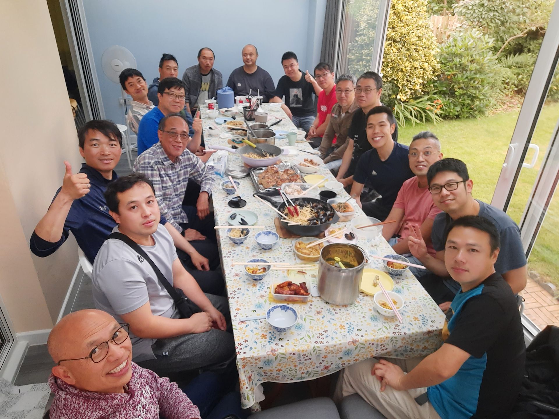 A group of men are sitting around a long table with food on it.