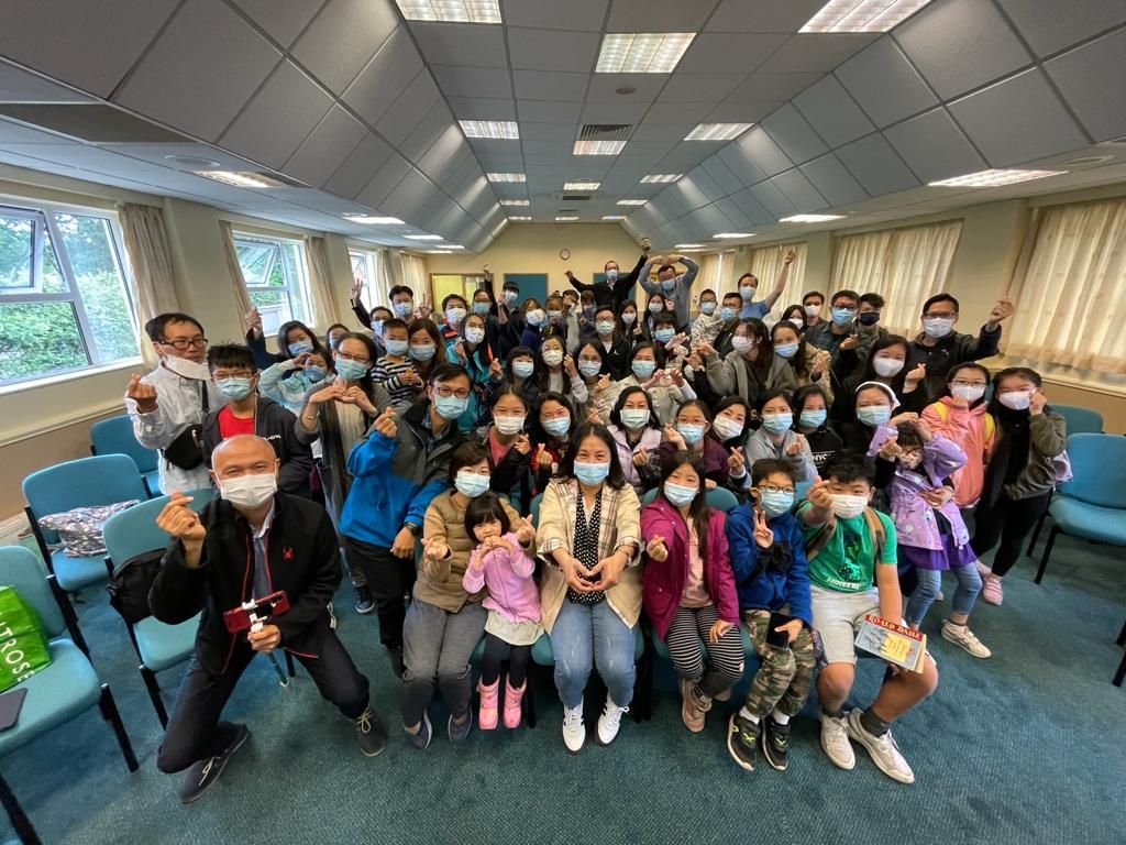 A large group of people wearing face masks are posing for a picture in a room.