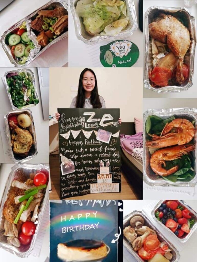 A woman is holding a sign that says `` happy birthday '' surrounded by a variety of food.