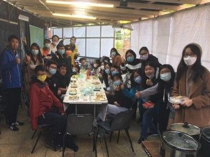 一群戴著口罩的人圍著一張長桌站著。