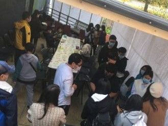 一群戴著口罩的人圍著一張桌子站著。