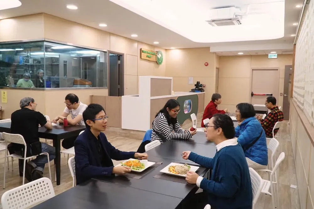一群人坐在一家餐廳的桌子旁吃食物。