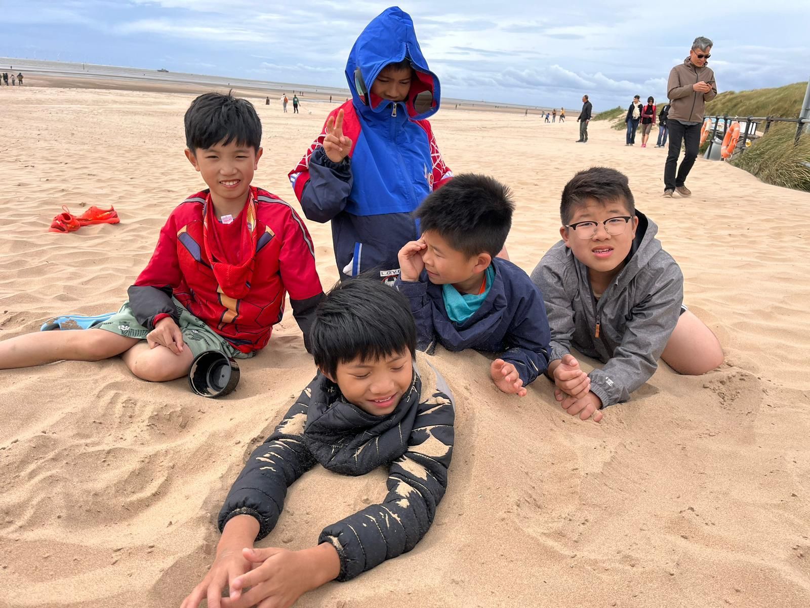 一群小男孩躺在海灘上的沙上。