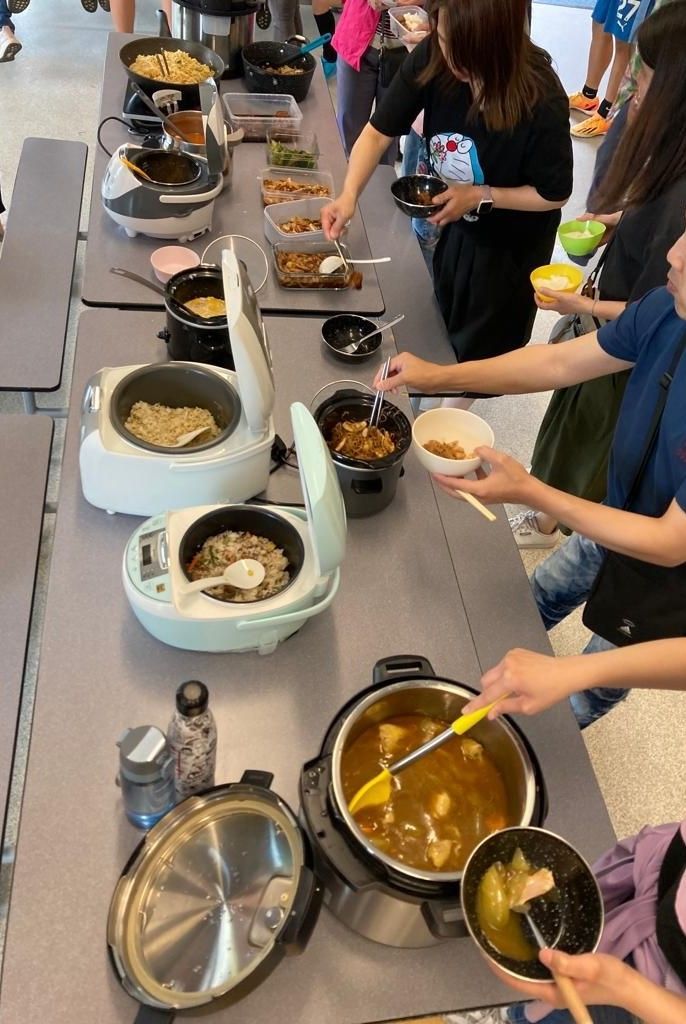 一群人坐在一張桌子旁，吃著鍋碗瓢盆裡的食物。