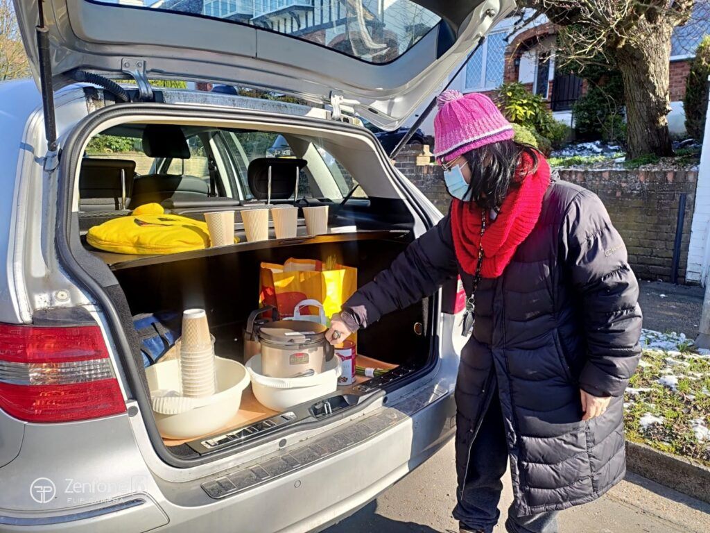 一名戴著口罩的女子正在打開汽車後車箱。