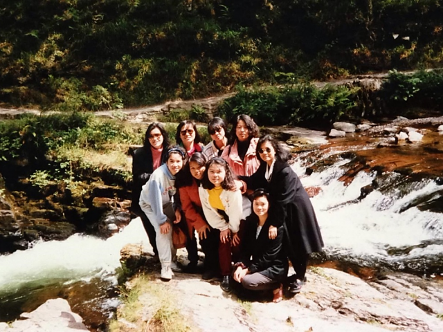 A group of women posing for a picture in front of a waterfall