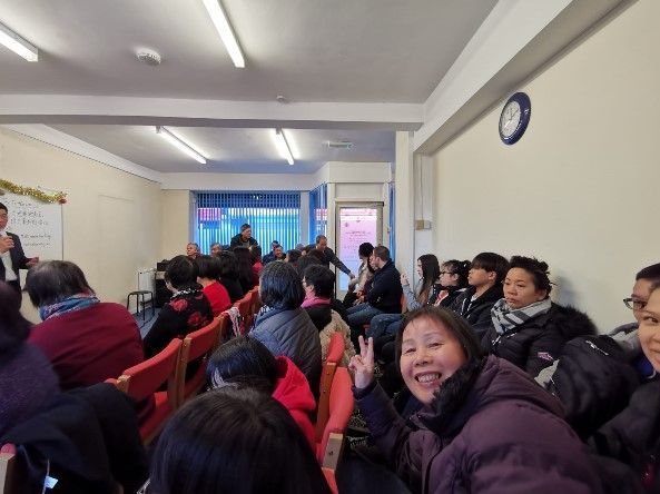 一群人坐在一個房間裡，牆上掛著一個鐘