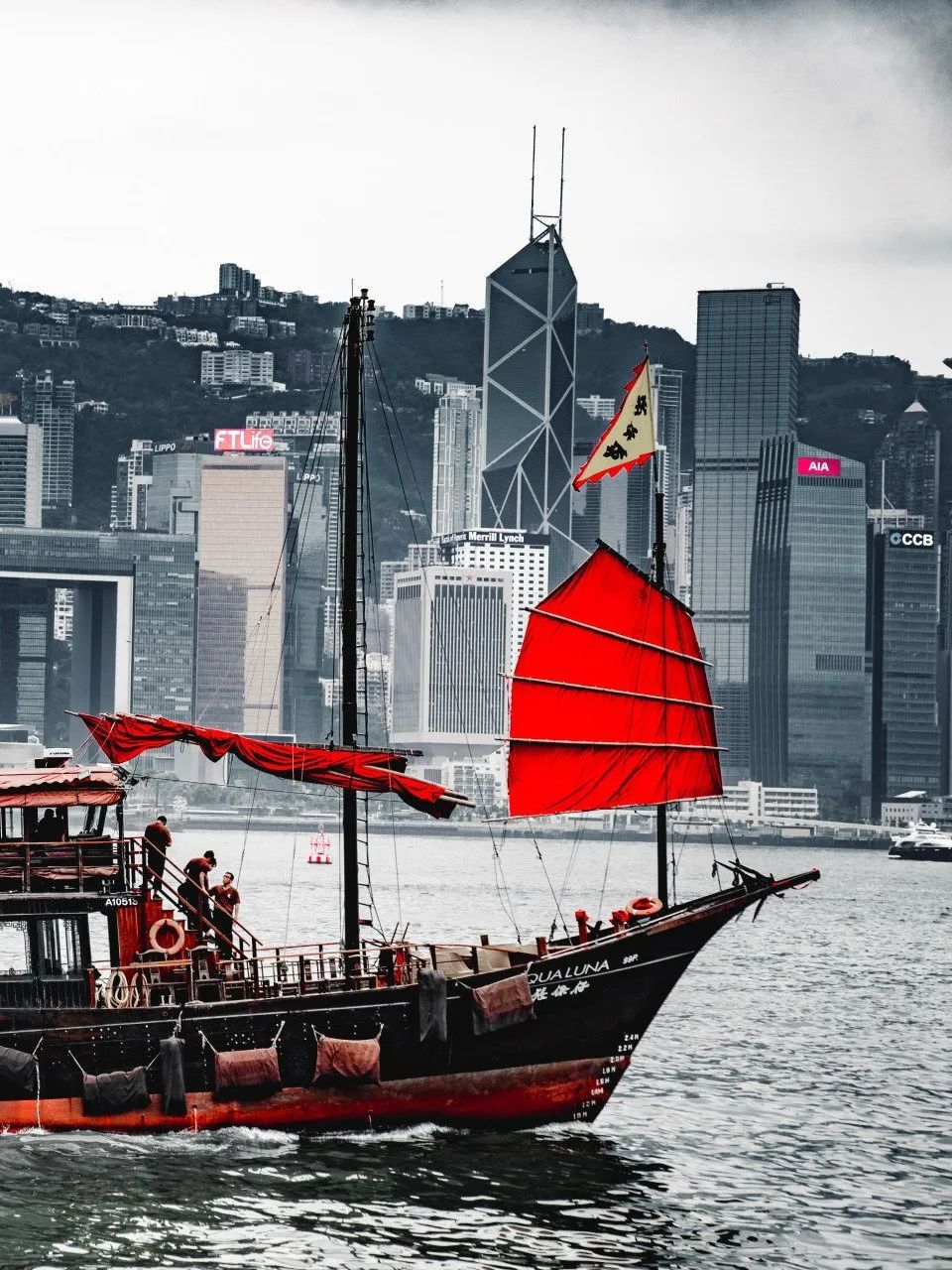 A boat with a red sail is floating in the water