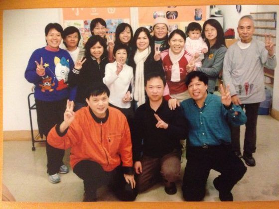 A group of people posing for a picture with one man wearing an orange jacket