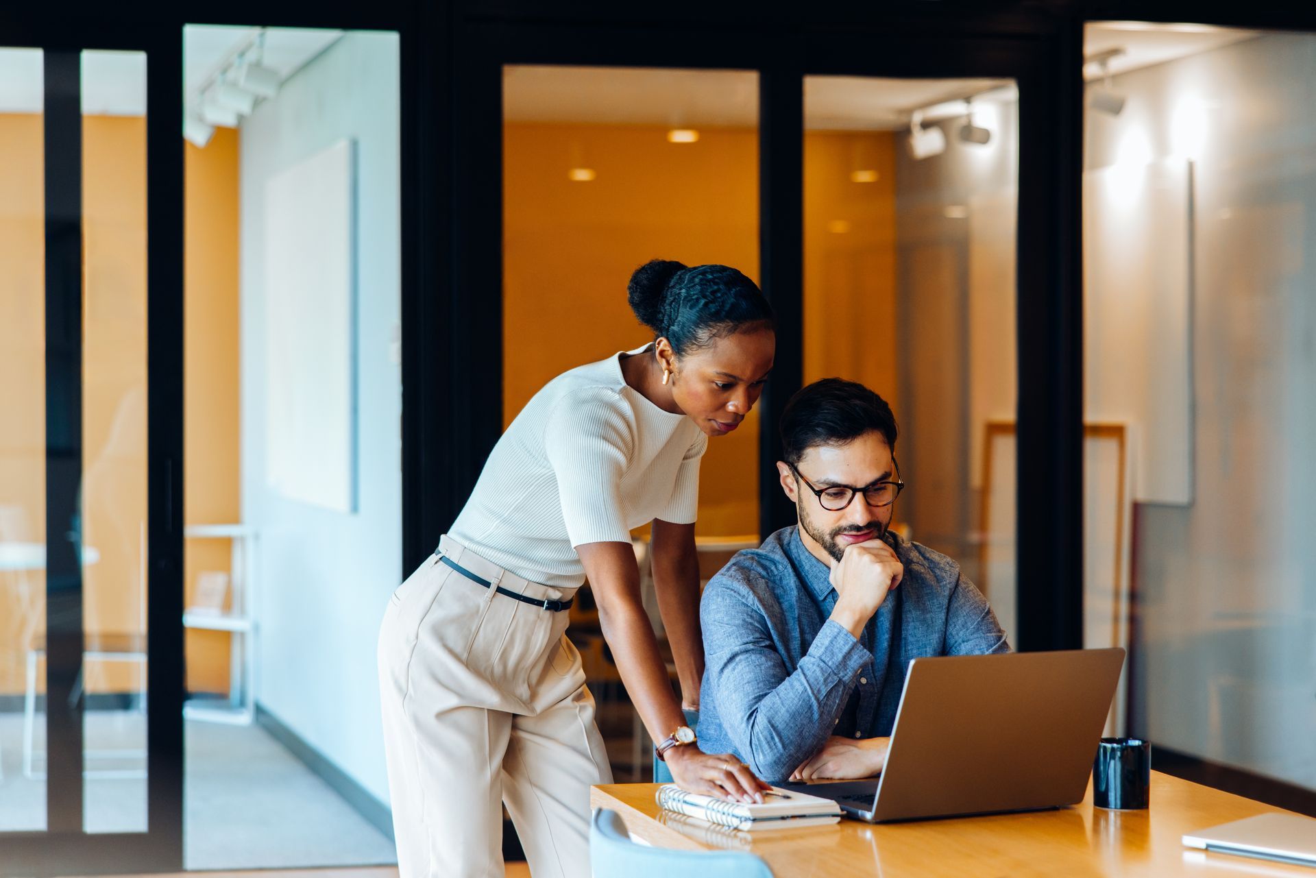 Two marketing professionals looking at a computer in a corporate office. 