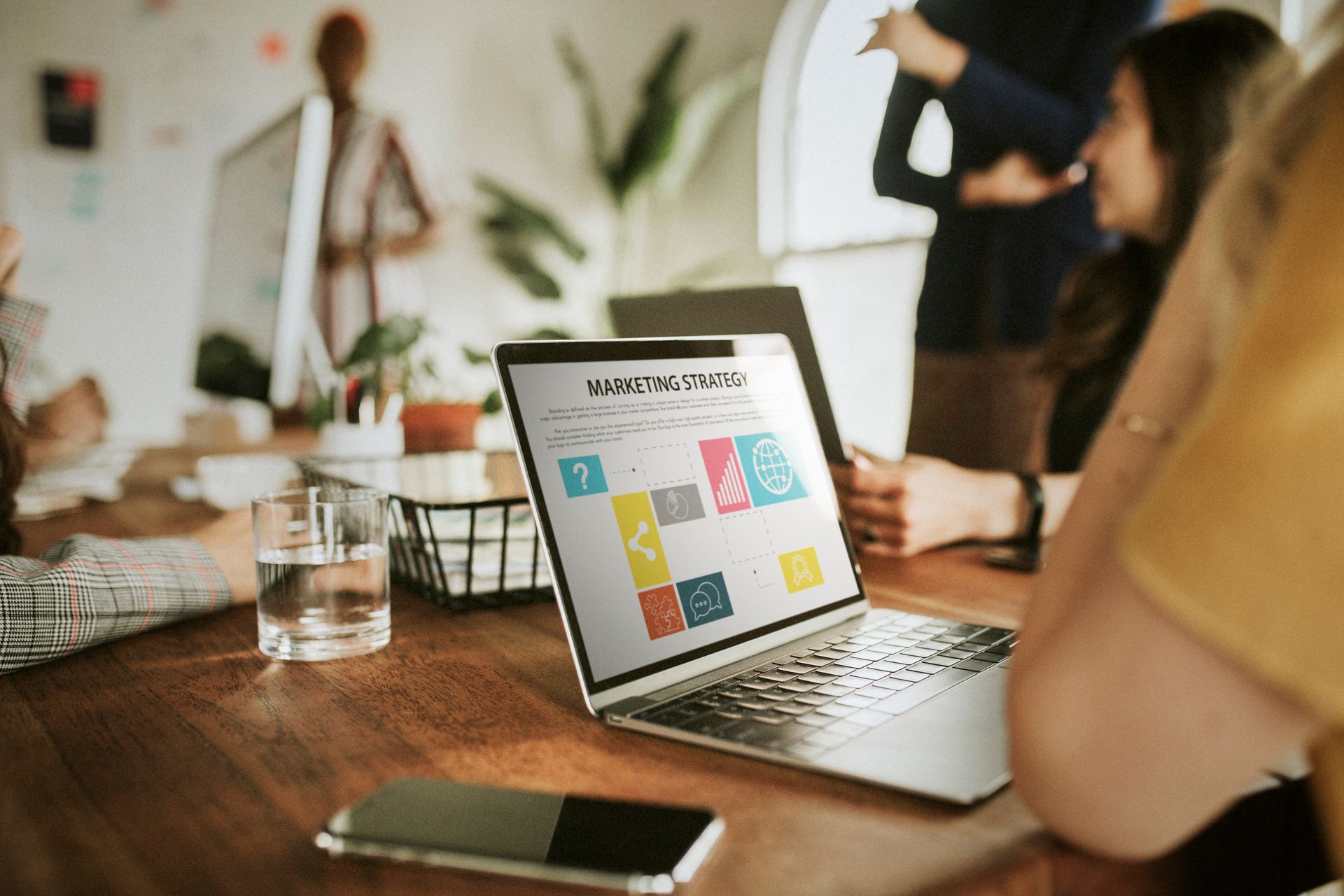 A marketing team discussing marketing strategies with a corresponding presentation on a laptop