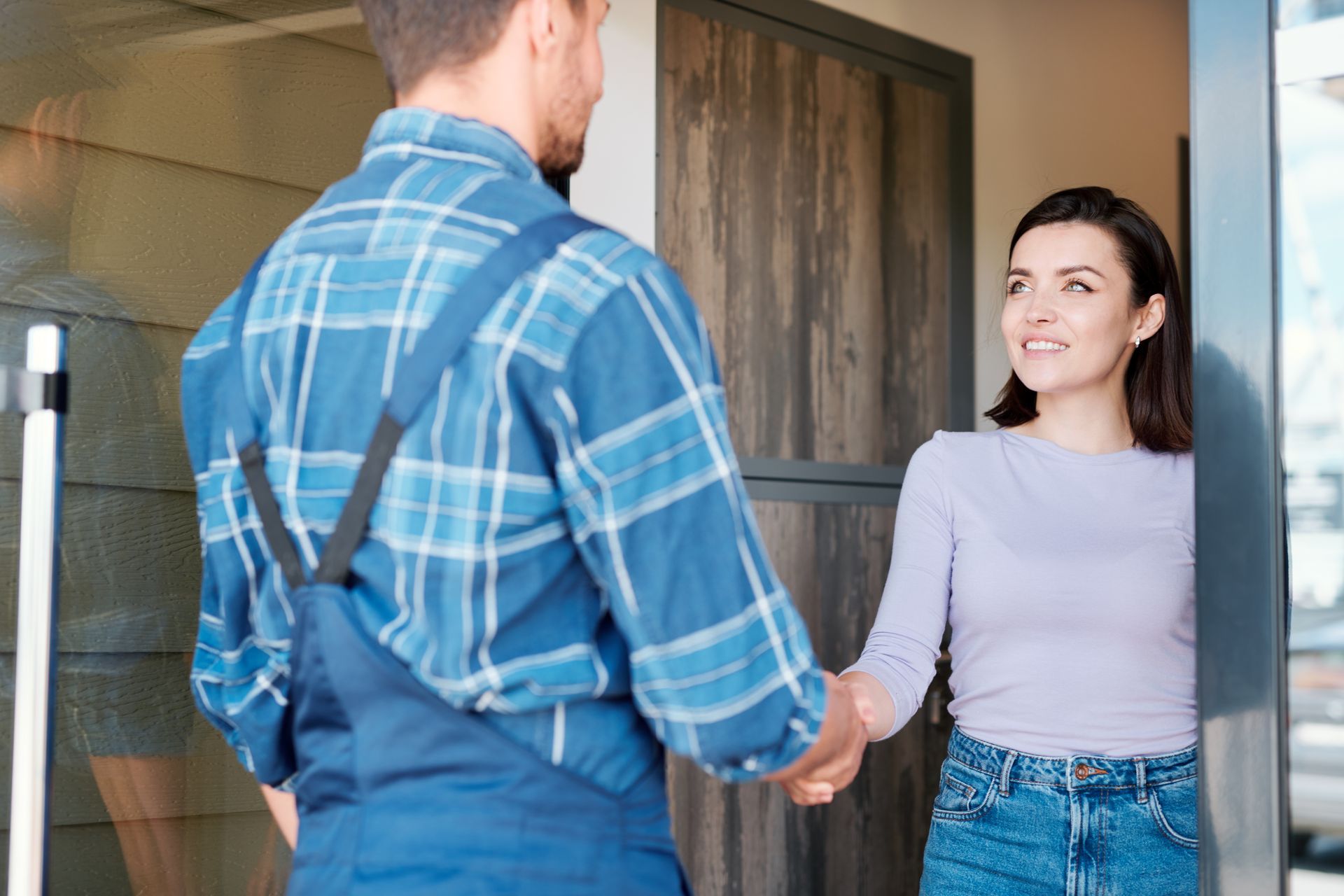 Homeowner shaking hands with a maintenance worker at the doorway
