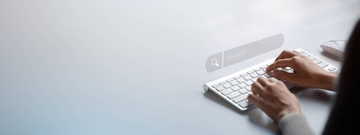 A person typing on a keyboard with a hologram search box