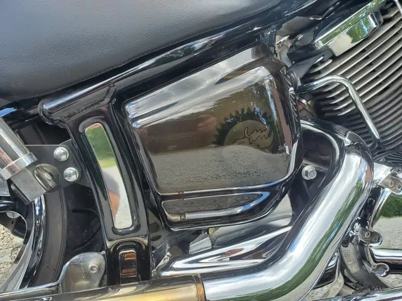 Black motorcycle side panel with chrome accents; exterior shot.