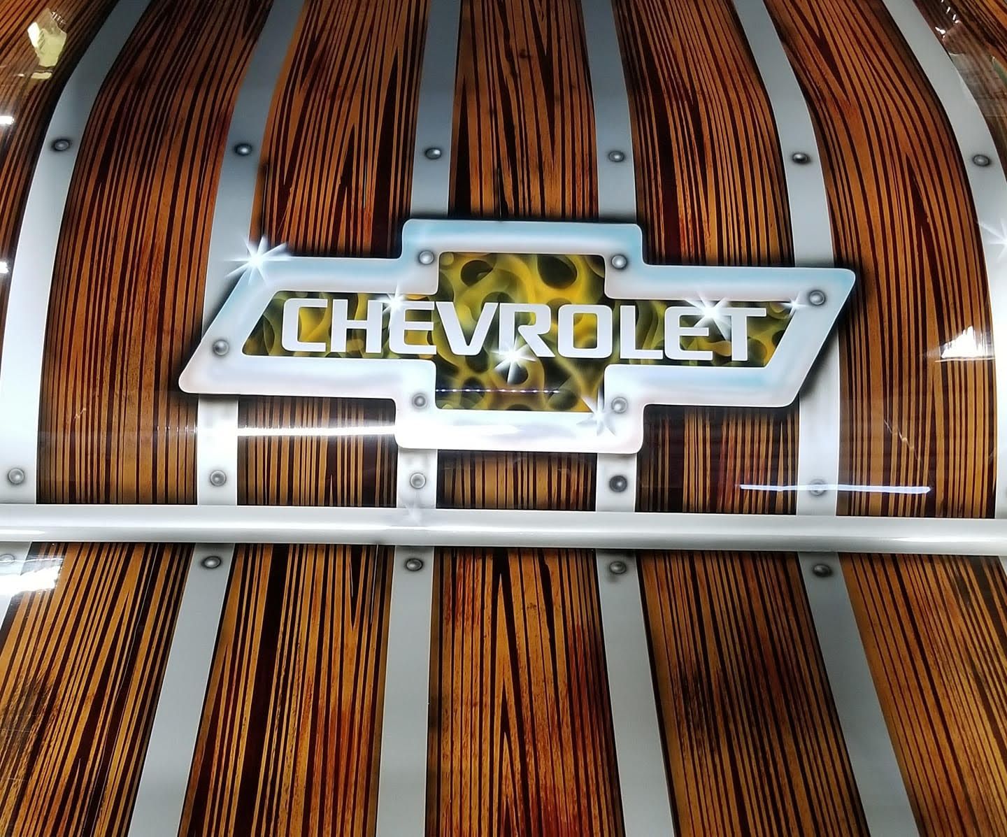 Chevrolet logo on a wooden background with silver accents.