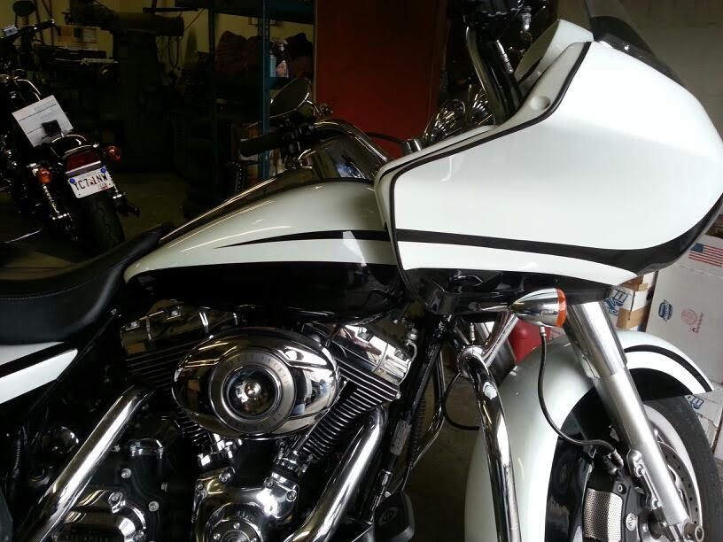 White and black Harley-Davidson motorcycle with fairing, parked in a garage.