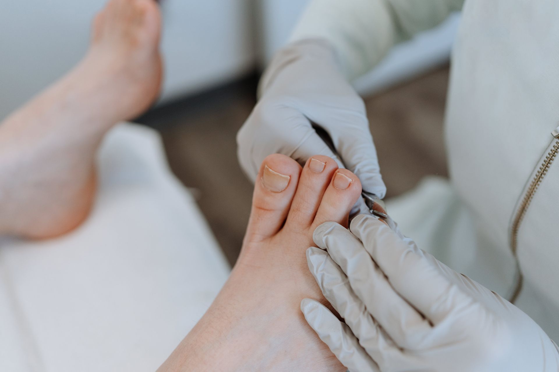 Gloved hands trimming toenails on a person’s foot during a pedicure