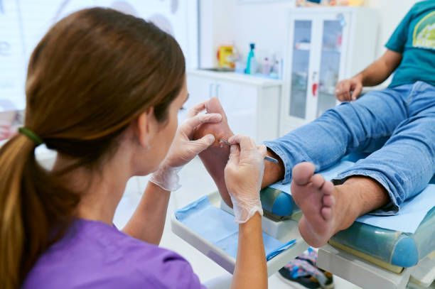 Dentist examining a patient’s foot in a clinic, with gloved hands and medical tools nearby