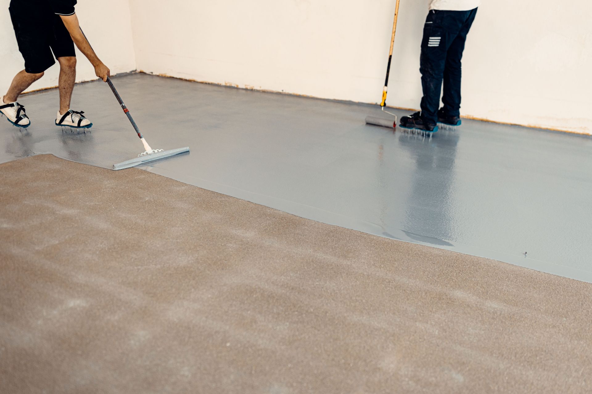 A Person is Cleaning a Concrete Floor With a Broom — Supremacy Painting Co In White Rock, QLD