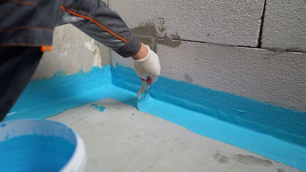 A Person is Painting a Wall With Blue Paint — Supremacy Painting Co In Edmonton, QLD
