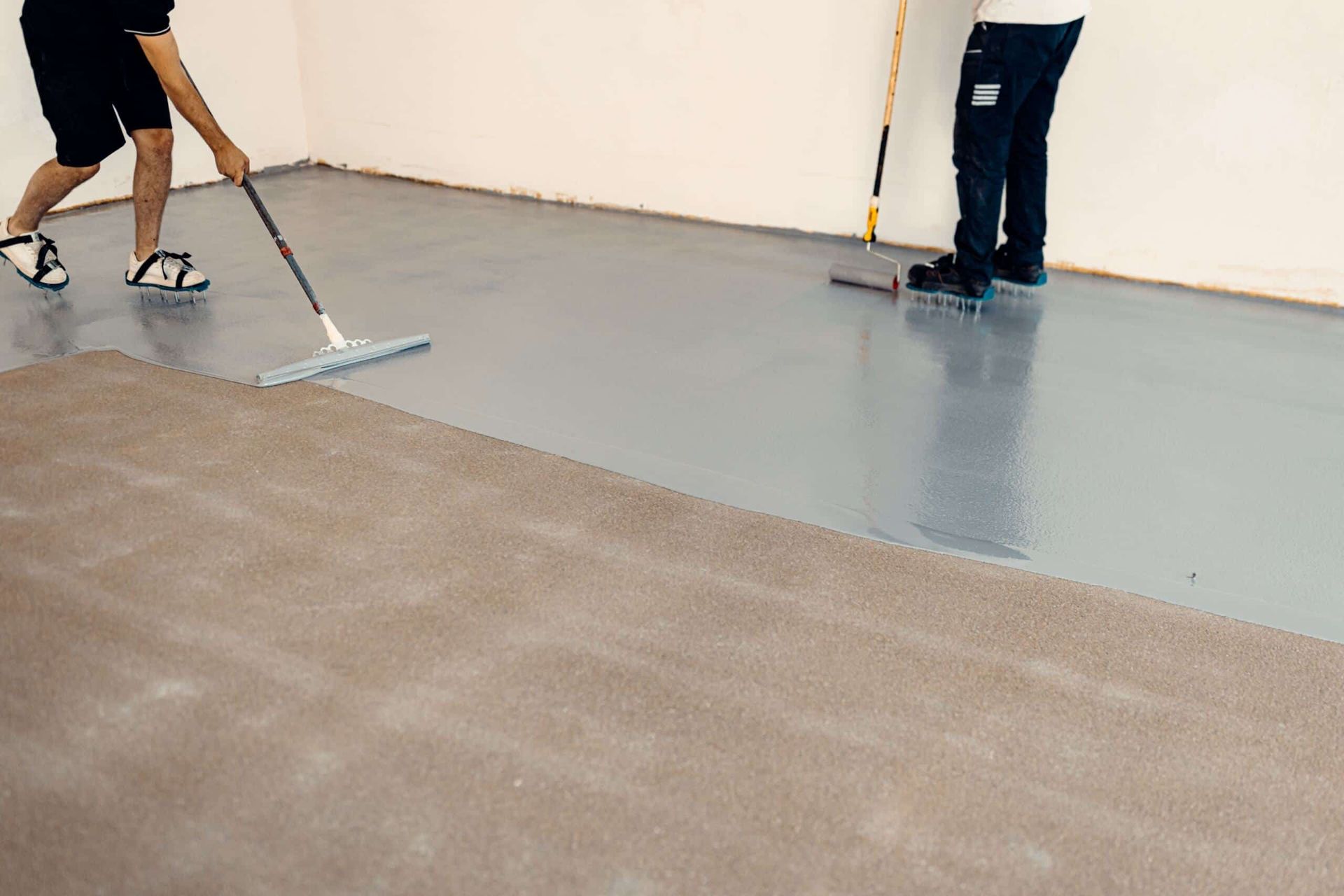 Two Men Are Painting a Concrete Floor With a Broom — Supremacy Painting Co In White Rock, QLD