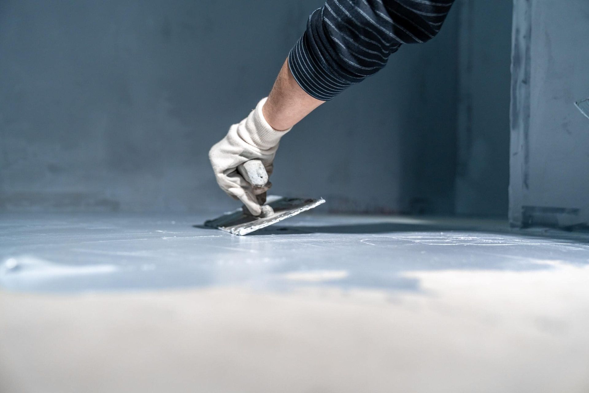 A Person is Plastering a Floor With a Trowel — Supremacy Painting Co In White Rock, QLD