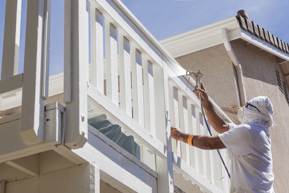 A Man is Spray Painting a White Railing on a Balcony — Supremacy Painting Co In Redlynch, QLD