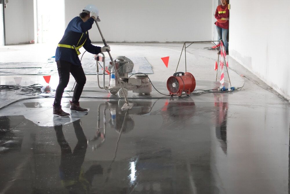 A Man is Using a Machine to Polish a Concrete Floor — Supremacy Painting Co In White Rock, QLD