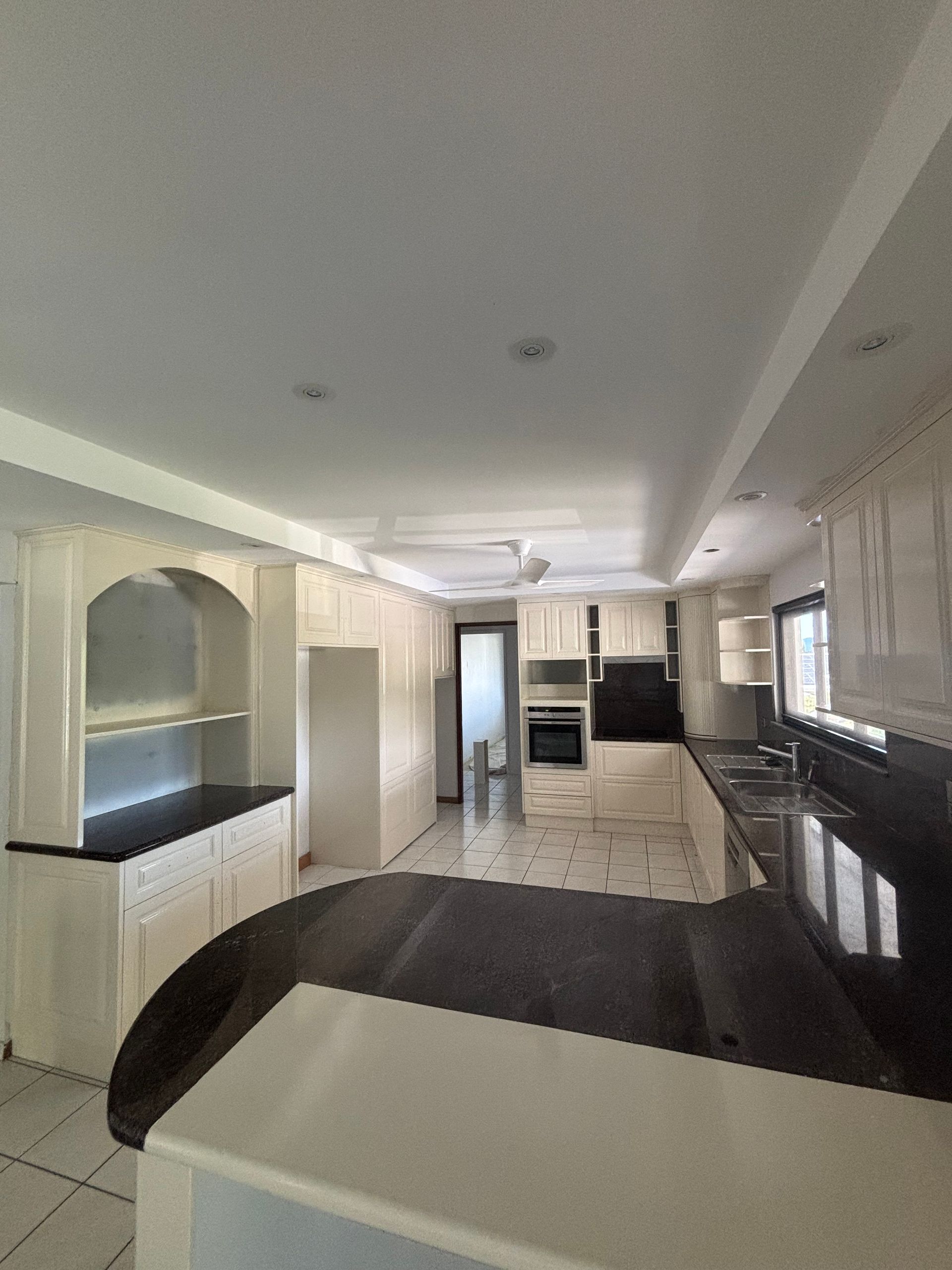 A Hand Holding a Spray Gun to Apply White Paint to a Surface — Supremacy Painting Co In Redlynch, QLD
