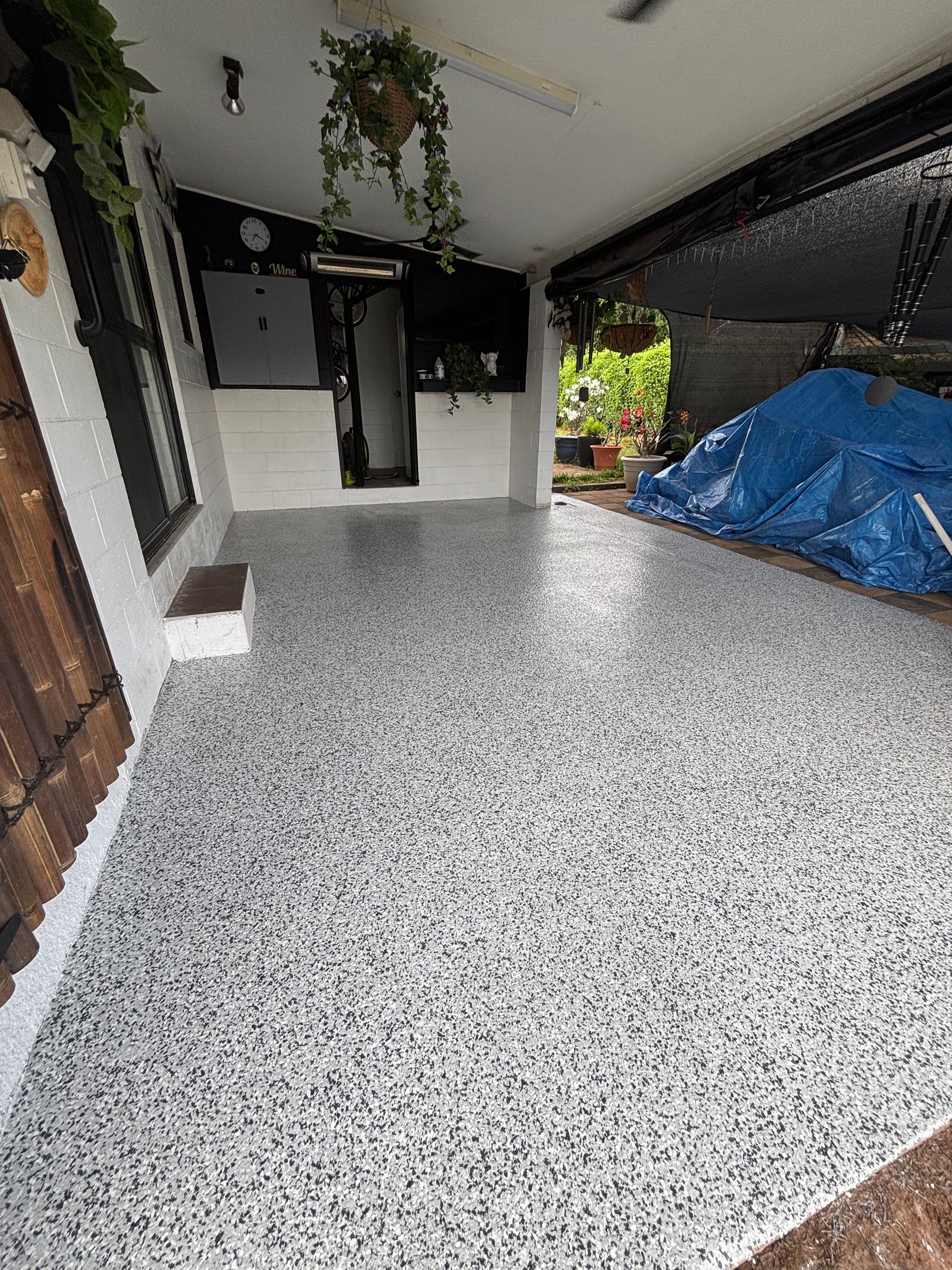A Man is Painting a Concrete Floor With a Roller — Supremacy Painting Co In White Rock, QLD
