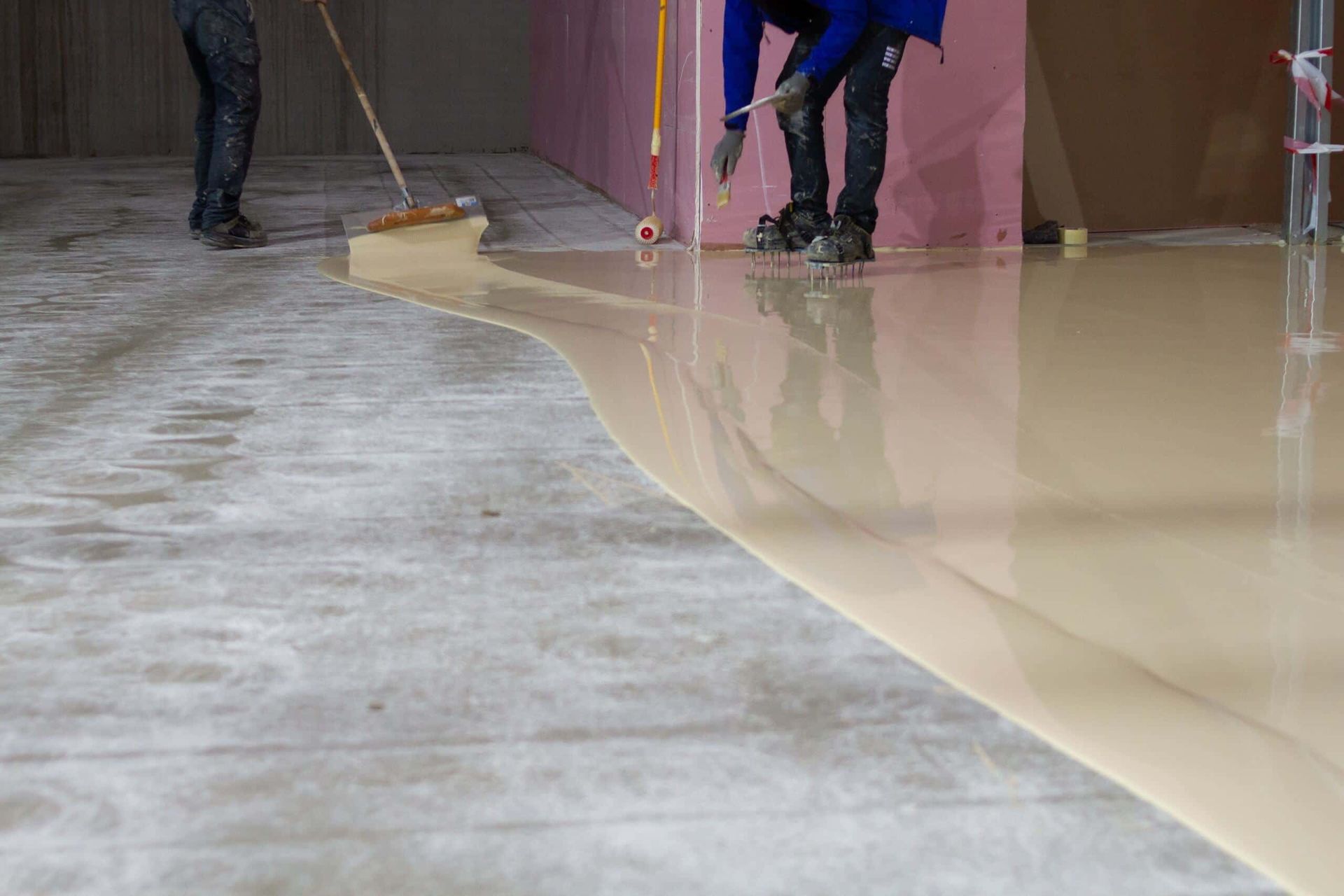 A Man is Painting a Concrete Floor With a Roller — Supremacy Painting Co In White Rock, QLD