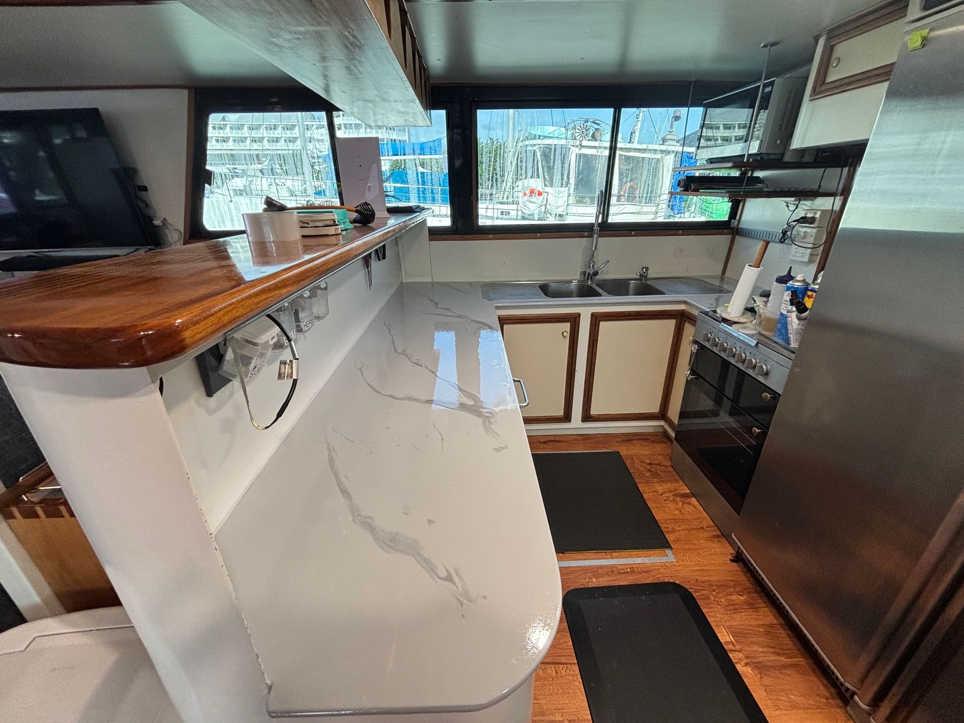 Modern kitchen with white island, wood counters, stainless fridge, and large windows overlooking water — Supremacy Painting Co In White Rock, QLD