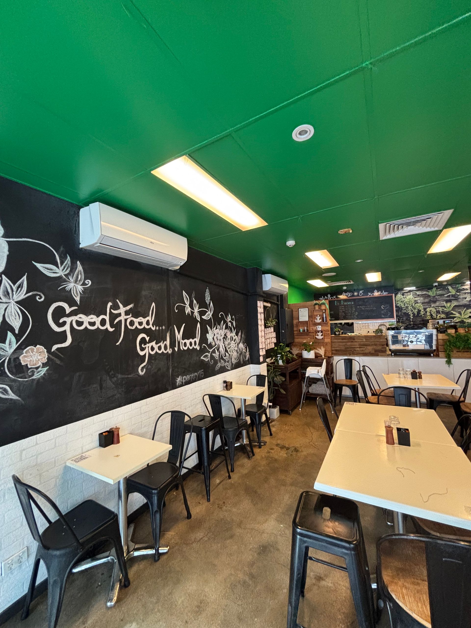 Small café interior with green ceiling, chalkboard wall, and tables and chairs along the seating area. — Supremacy Painting Co In White Rock, QLD
