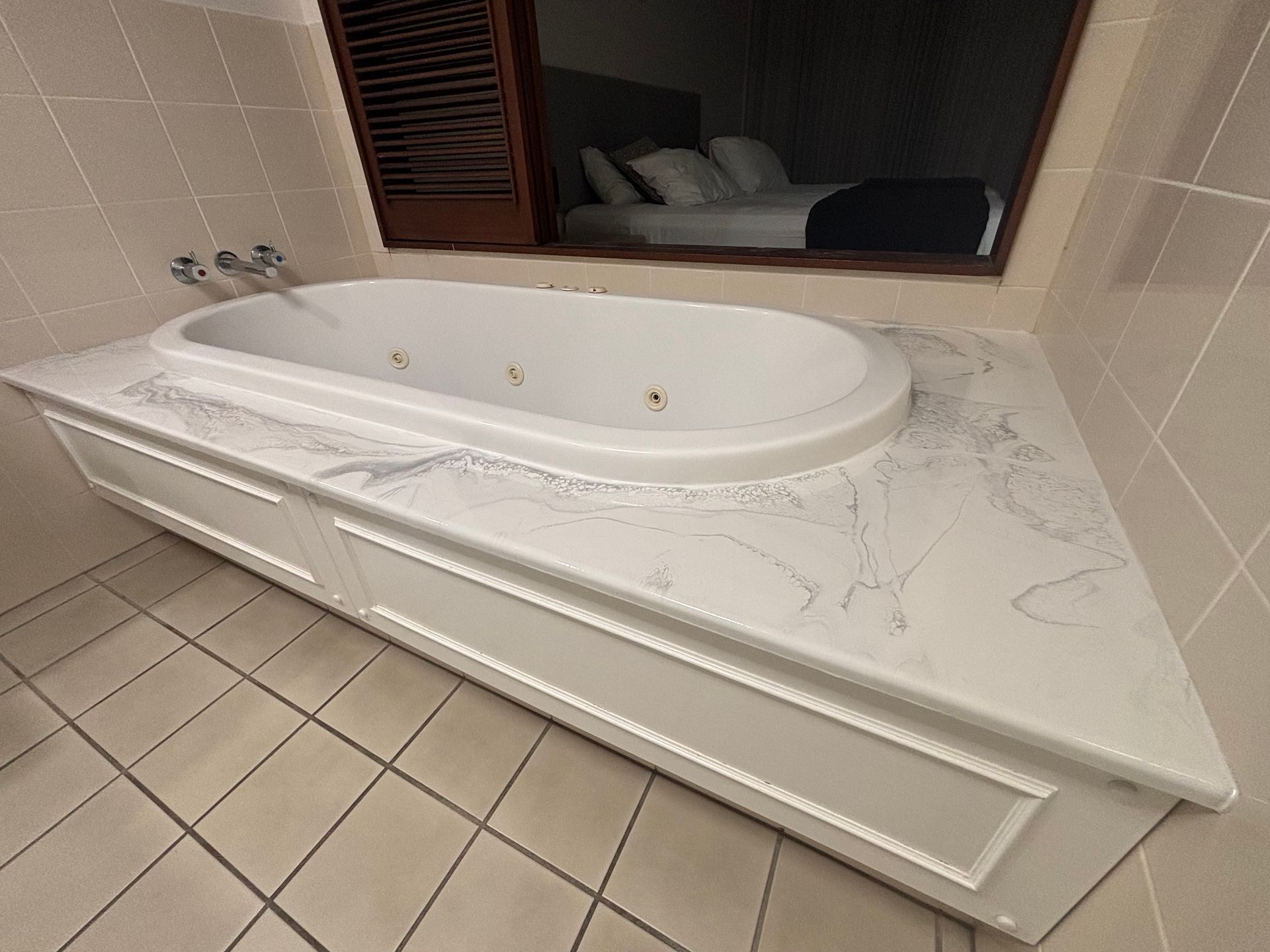 White corner bathtub with marble surround and tiled bathroom floor. — Supremacy Painting Co In White Rock, QLD