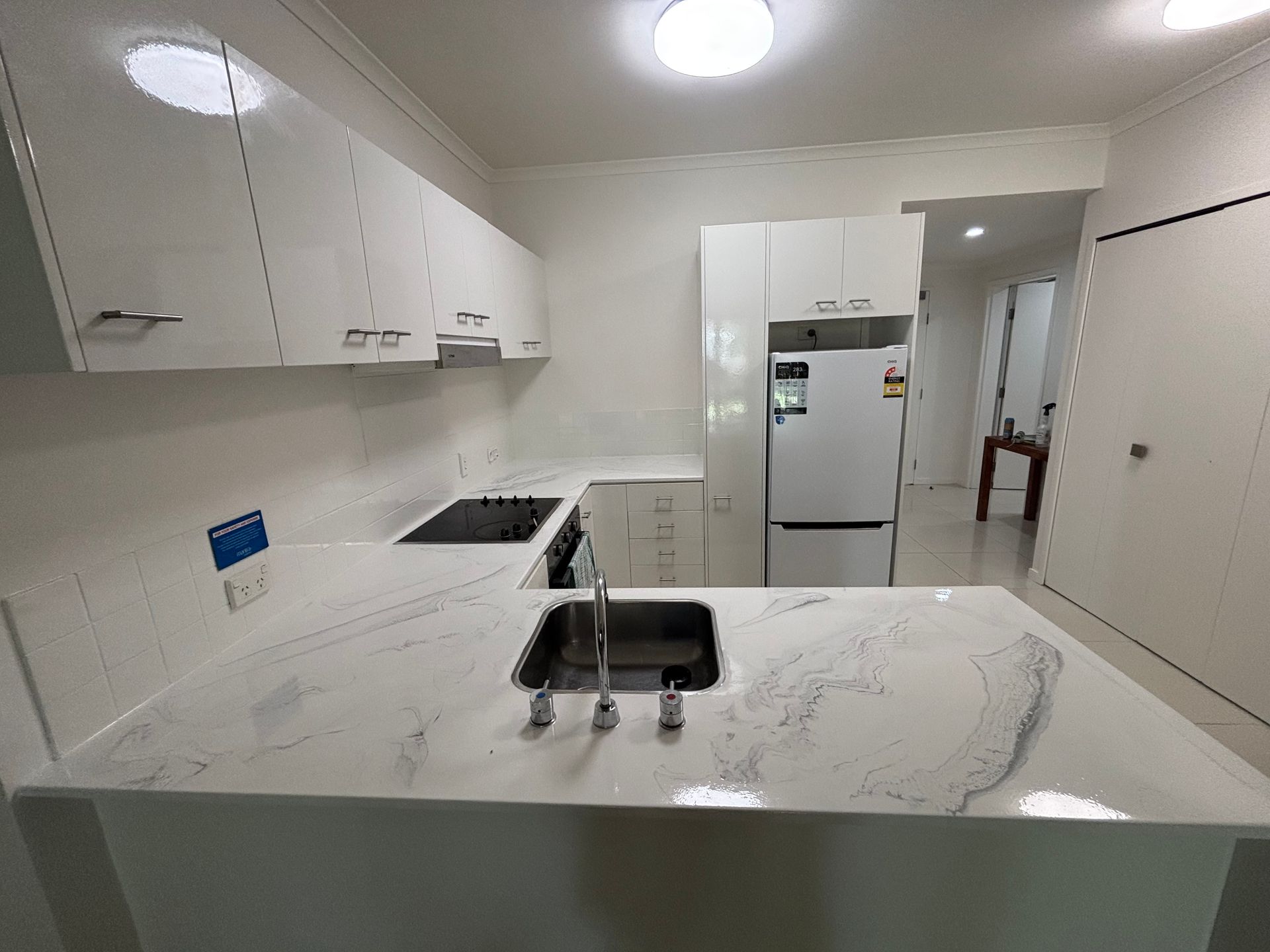 Bright modern kitchen with white cabinets, island, and refrigerator. — Supremacy Painting Co In White Rock, QLD