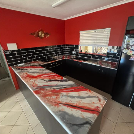 Modern kitchen with red walls, black subway tile, and a gray-red marbled countertop across a central island — Supremacy Painting Co In White Rock, QLD