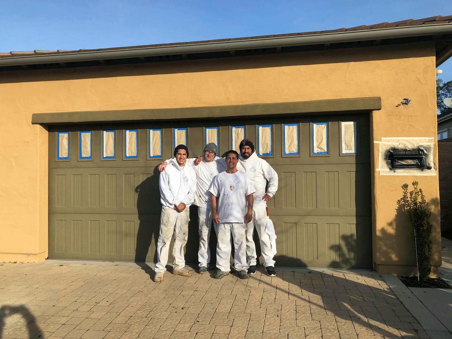 A group of men are standing in front of a garage door.