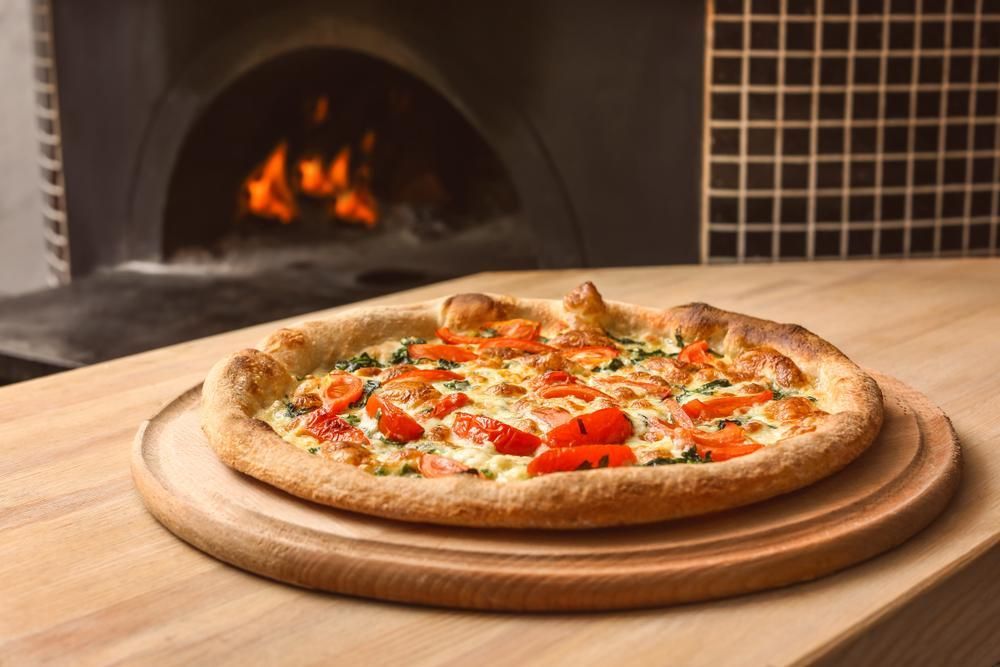 A Pizza Is Sitting on A Wooden Cutting Board on A Table — Gungahlin Kebab and Pizza in Gungahlin, ACT