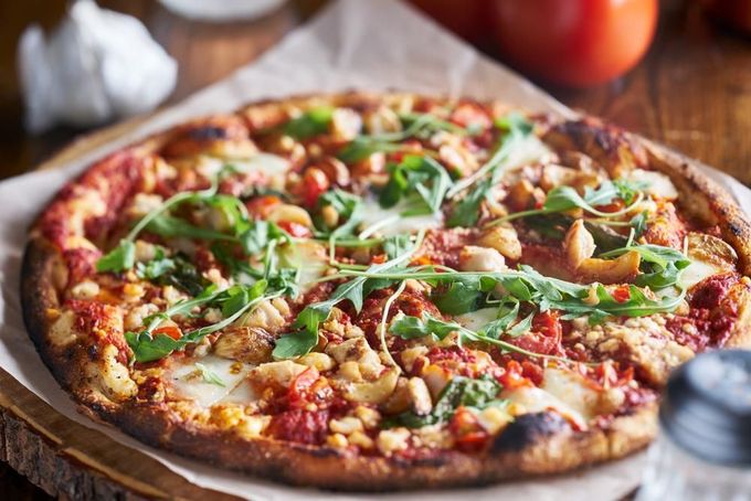 A Pizza Is Sitting on A Wooden Cutting Board on A Wooden Table — Gungahlin Kebab and Pizza in Gungahlin, ACT
