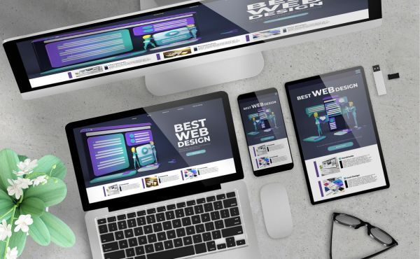 A laptop , tablet , phone , and monitor are sitting on a table.