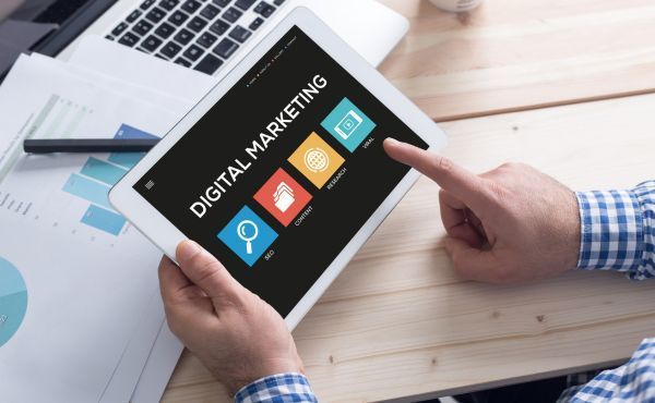 A person is holding a tablet that says digital marketing on it.