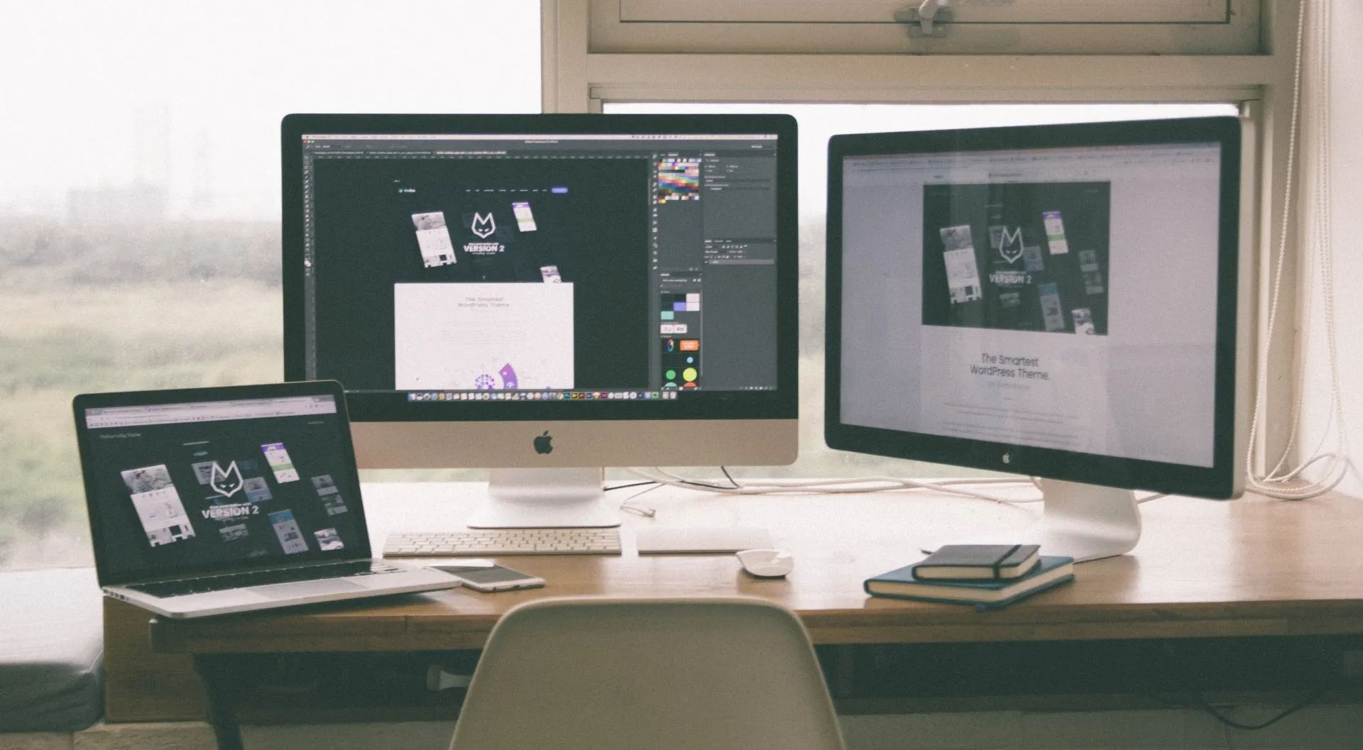 A desk with two computer monitors and a laptop on it.