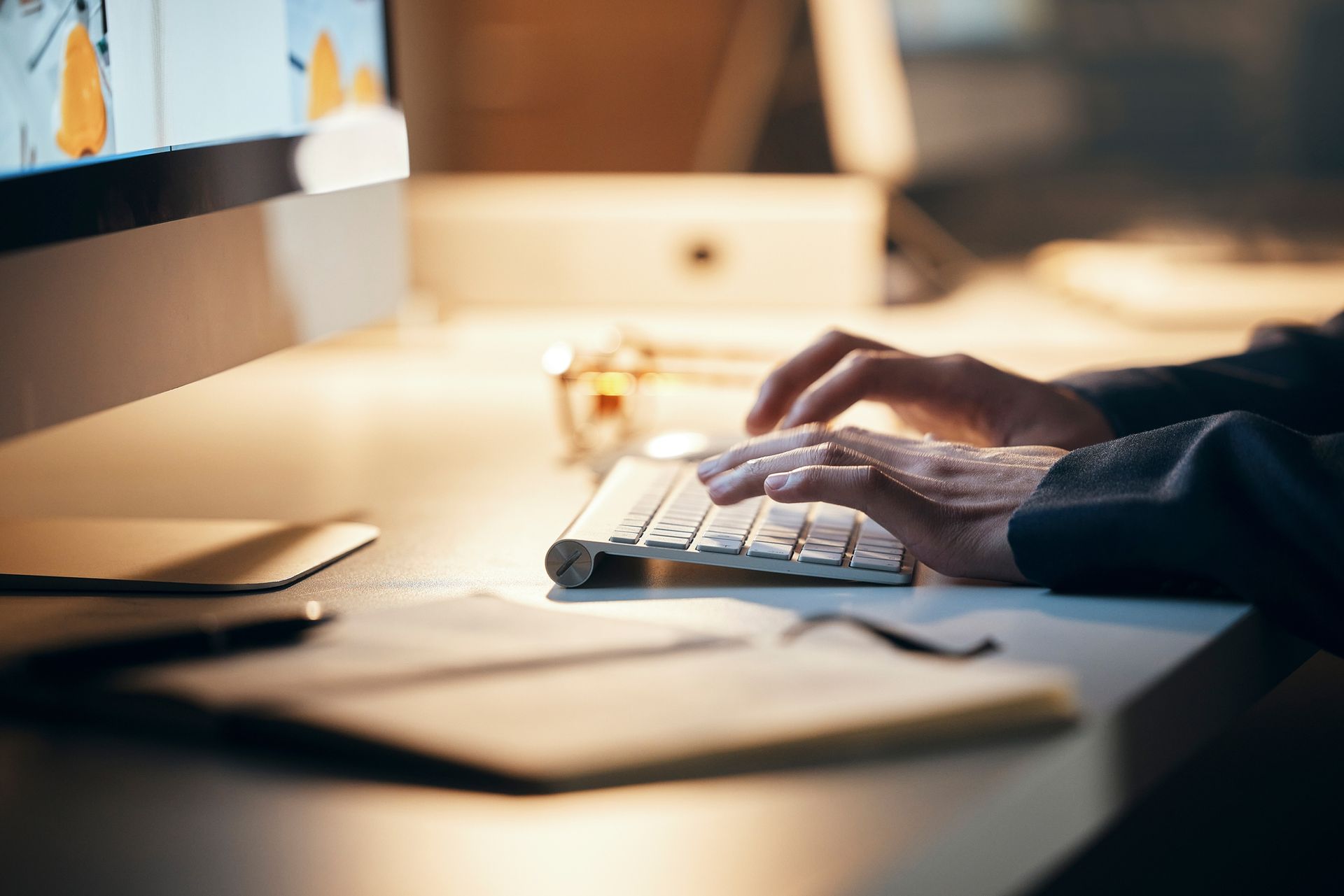 A person is typing on a keyboard in front of a computer.