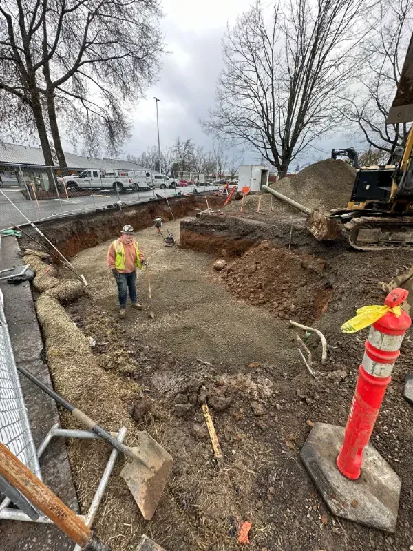 A construction worker is walking through a hole in the ground in Vancouver, WA by NAVA Concrete LLC