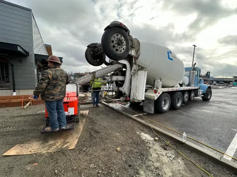 A concrete mixer truck is being loaded with concrete in a parking lot in Vancouver, WA