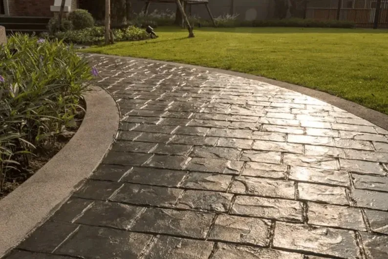 A curved stone walkway next to a grassy lawn.